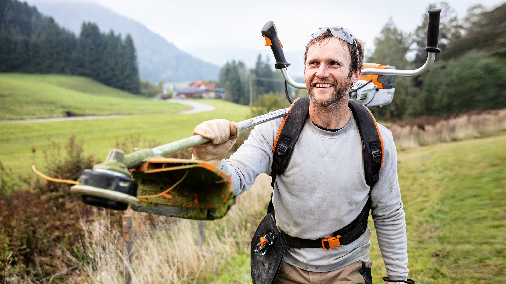 Homem com aparadora STIHL e arnês universal Advance PLUS num prado