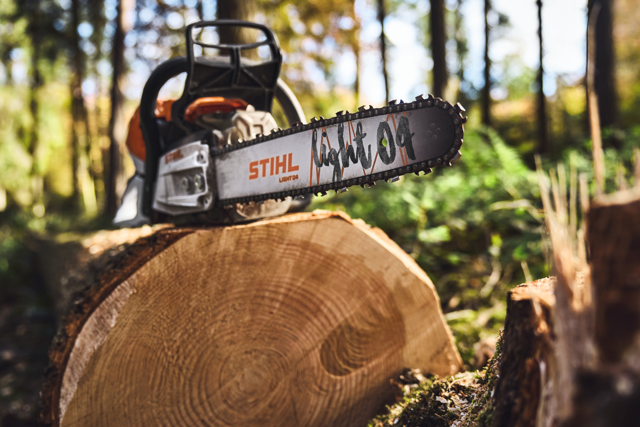 Primer plano de una motosierra STIHL con la barra guía ligera 04 en un tocón de árbol en el bosque
