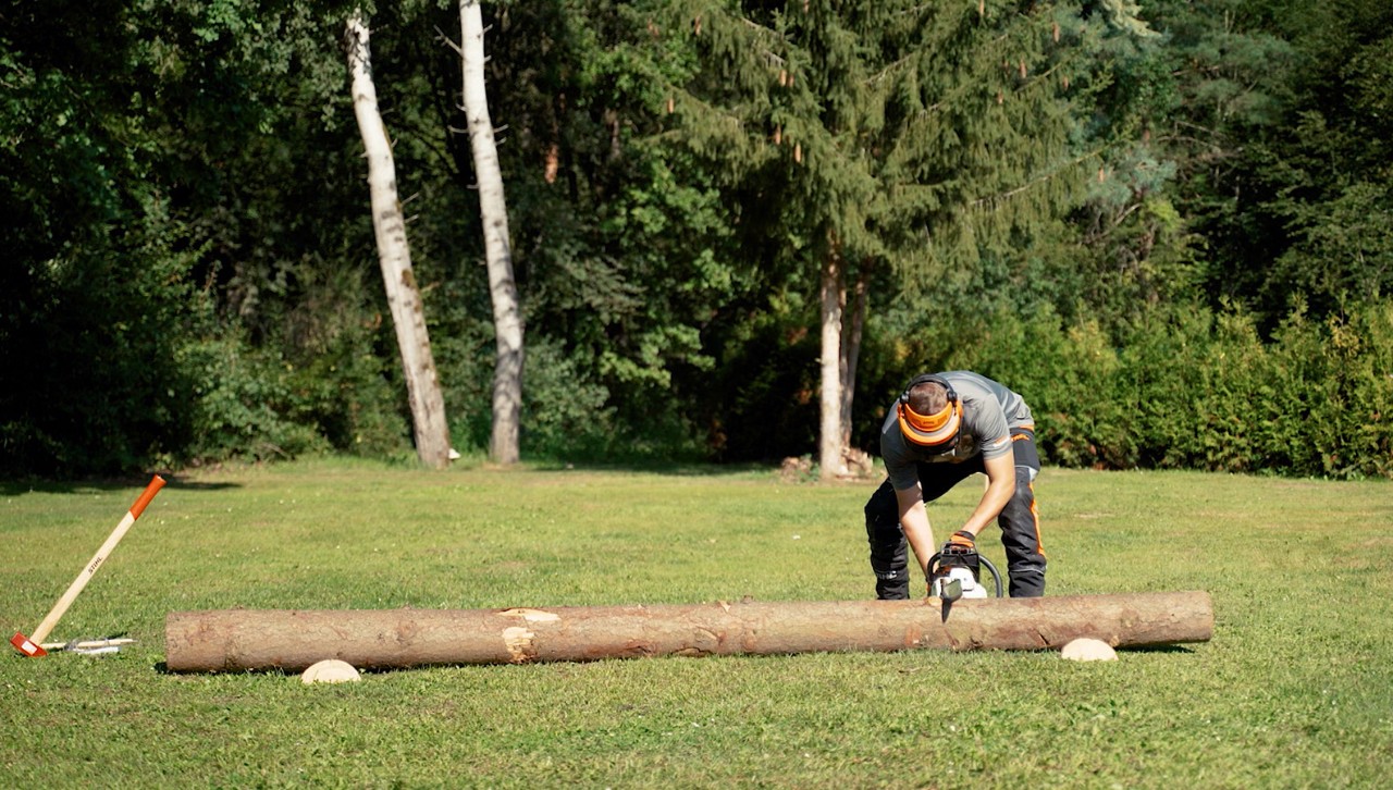 Una persona con equipamiento de protección usa una motosierra STIHL para cortar leña.
